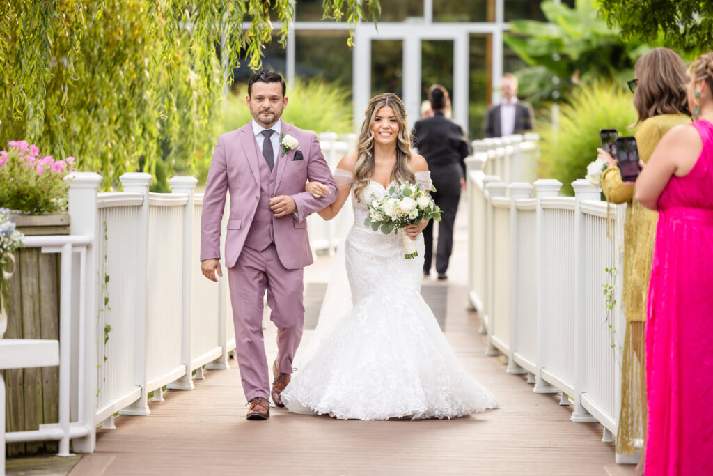 Bride and her dad walking down the aisle at the outdoor ceremony at Flowerfield. 