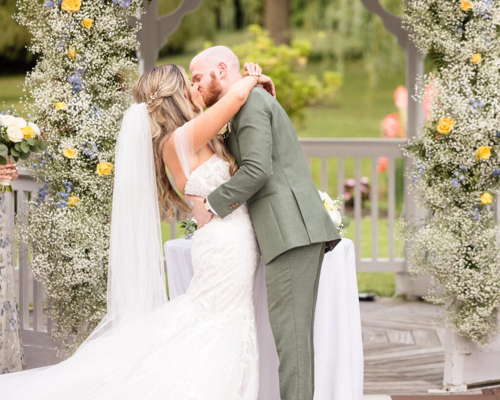 Bride and groom sharing their first kiss at the wedding ceremony.