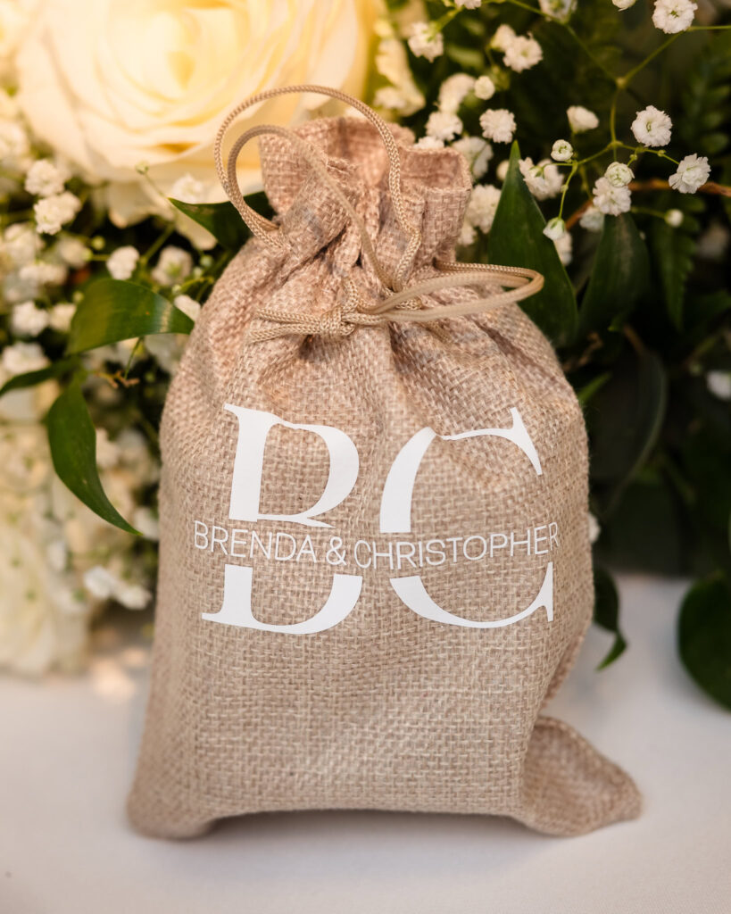 Burlap bag that contains a gift. The bag has the monogram of the bride and groom.