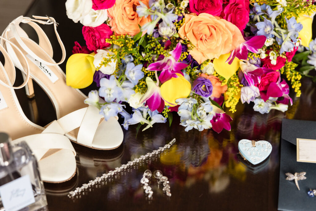 Bride's shoes, flowers, and jewelry on a table at the Garden City Hotel.