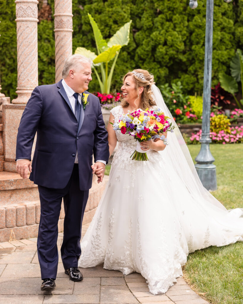 Bride and groom walking and holding hands in the garden at Sand Castle Wedding Venue.