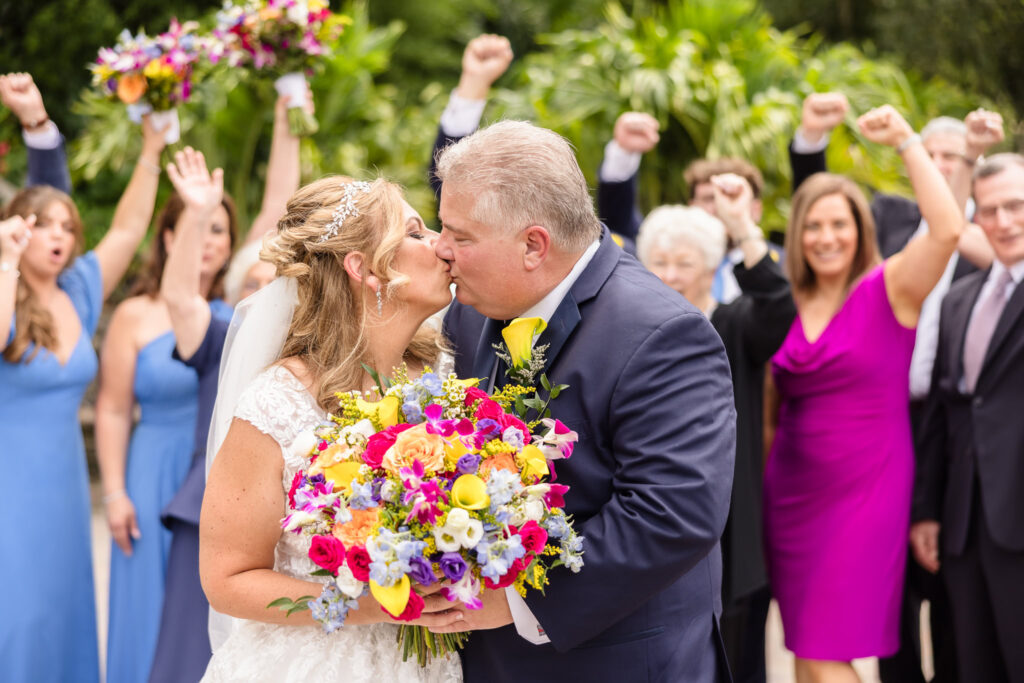 Bride and groom kissing in front of family and friends at Sand Castle Wedding Venue