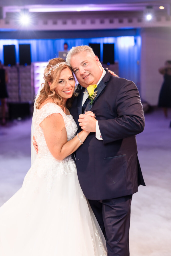 Bride and groom smiling at the camera during first dance while smoke fills the floor of the Sand Castle wedding venue.