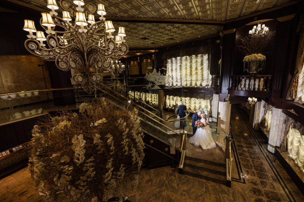 Bride and groom on stairs in lobby at Sand Castle wedding venue. The entire lobby can be seen.