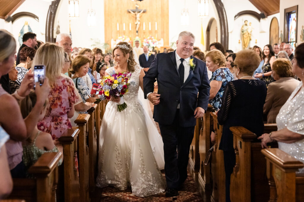 Bride and groom walking down the aisle after the ceremony while smiling at their guests.