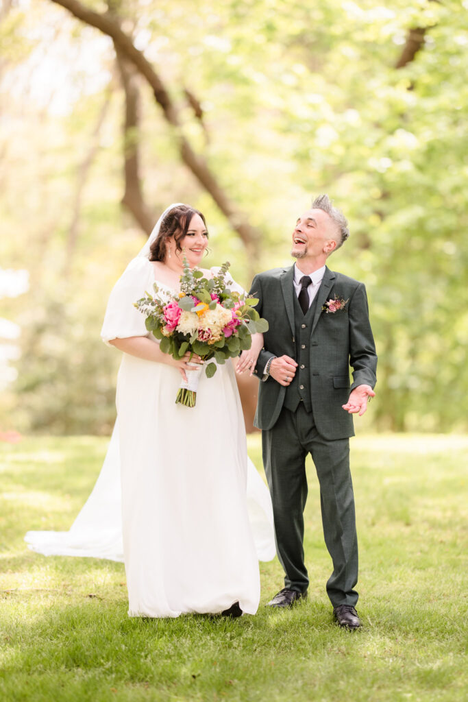 Bride and groom laughing while walking on grass at Bates House at Frank Melville Park.