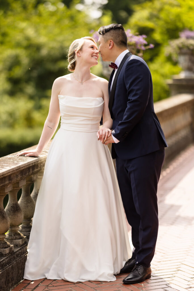 Bride and groom about to kiss next to railing at Old Westbury Gardens.