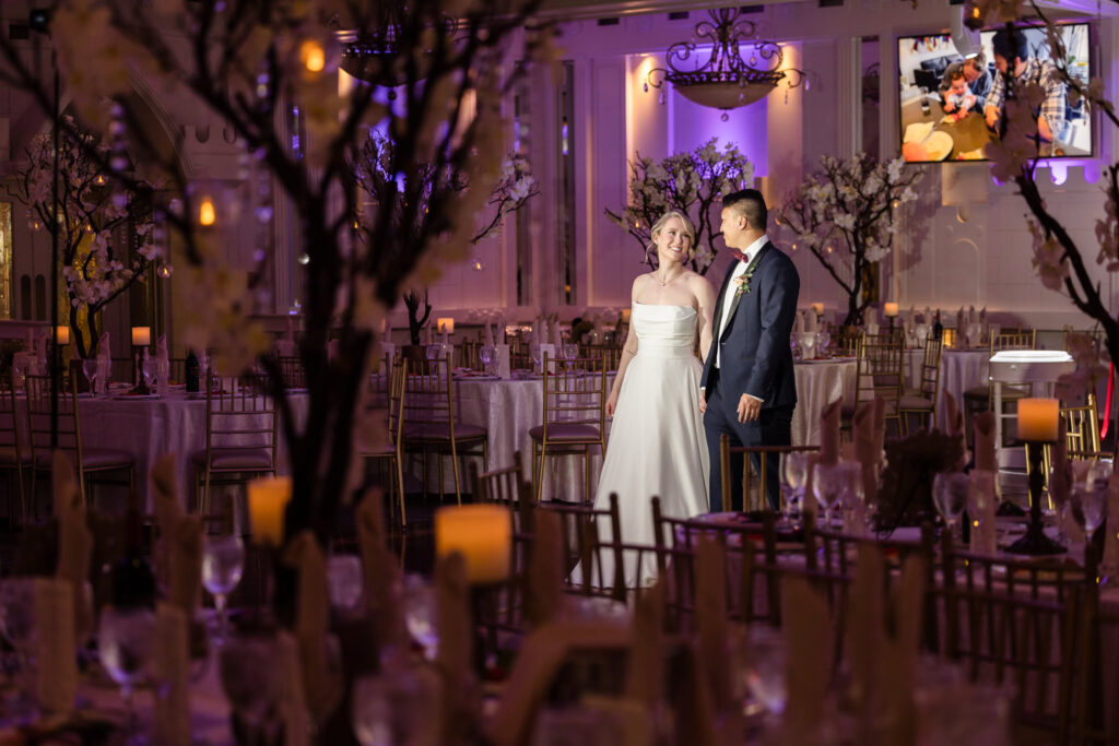 Bride and groom walking in ballroom at Sand Castle. They are alone in the room and smiling at each other. 