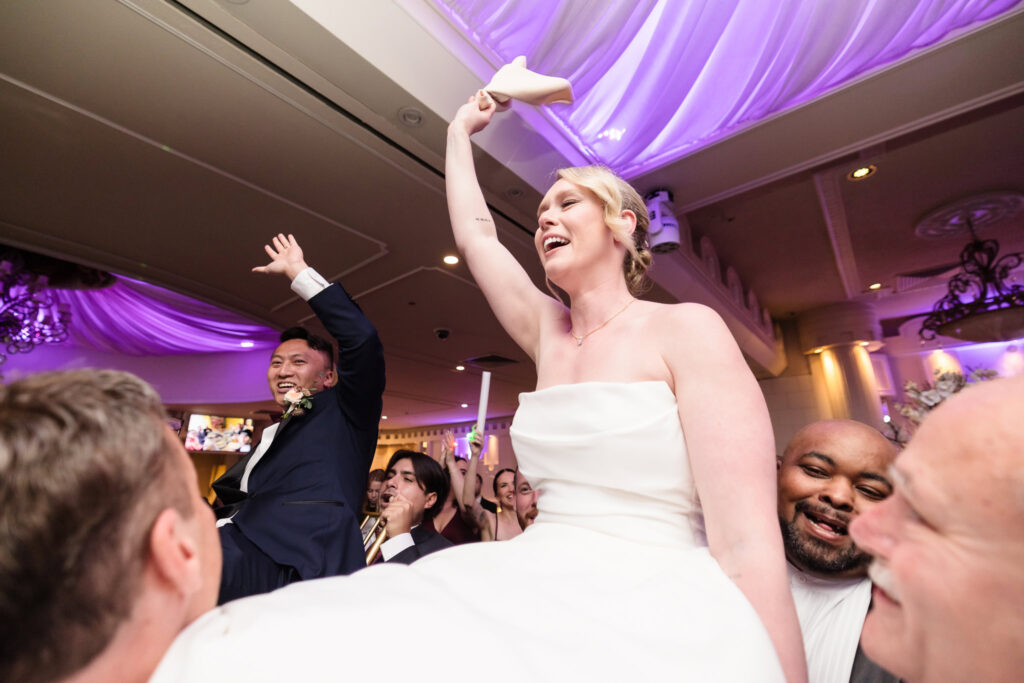 Bride and groom being raised on a chair. 