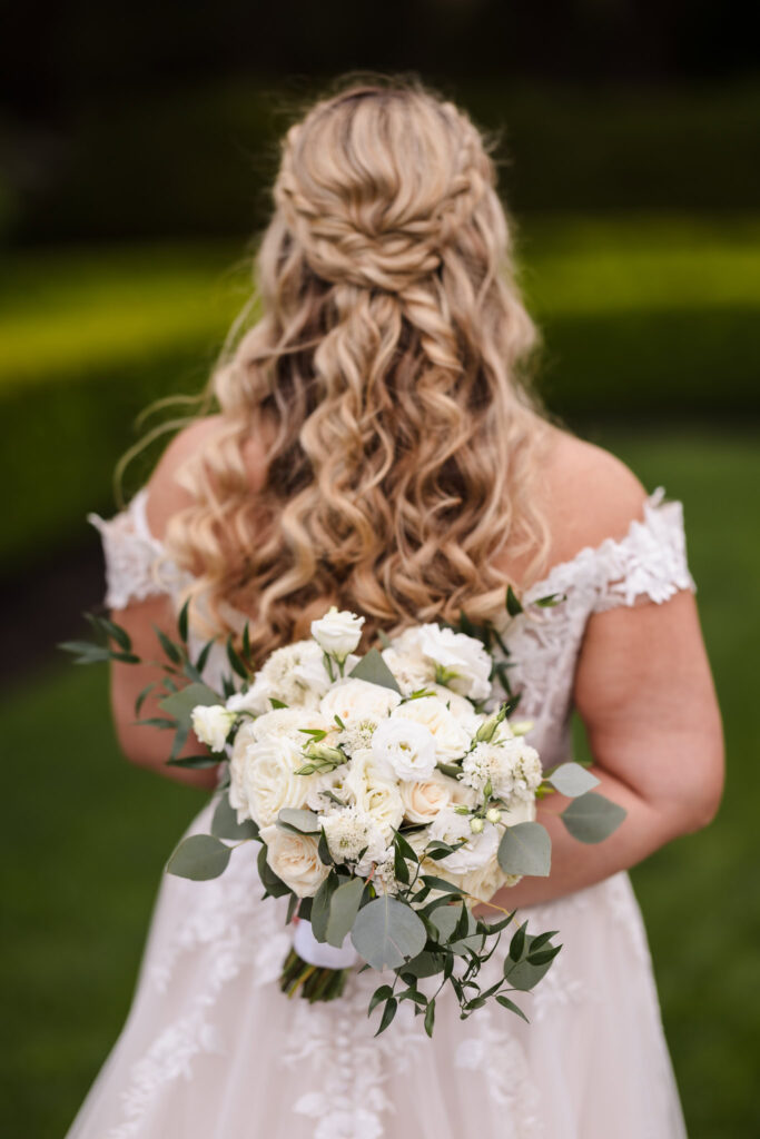 Bride holding her white bouquet behind her back. 