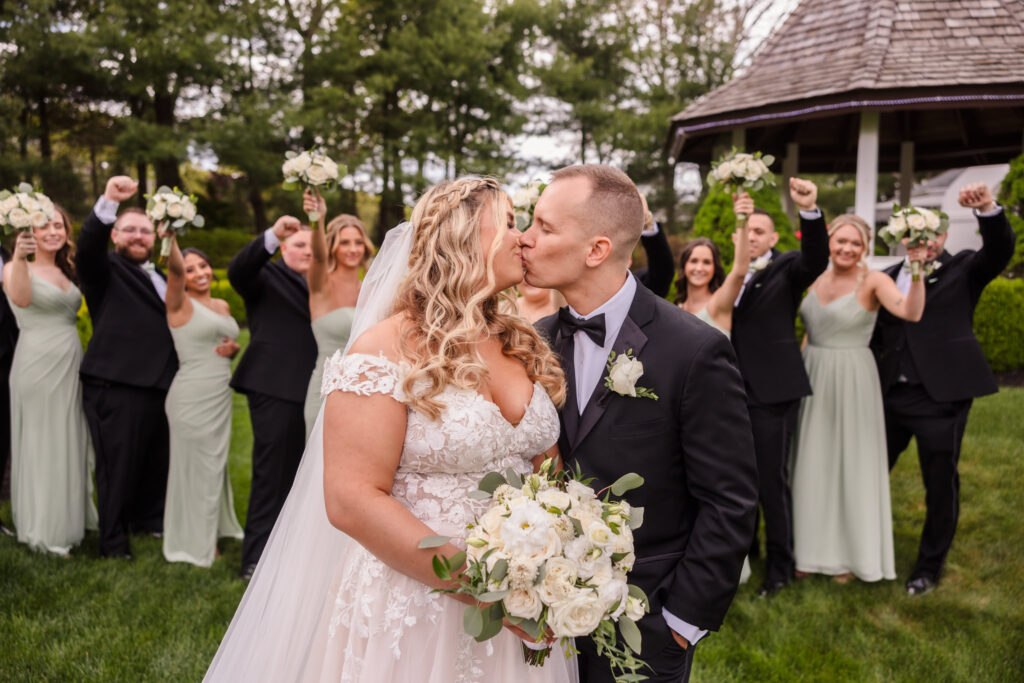 Bride and groom kissing in front of bridal party at The Vineyard at East Wind. The bride and groom are in focus and the wedding party is out of focus. 