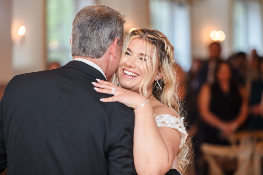 Bride smiling while dancing with her dad. 