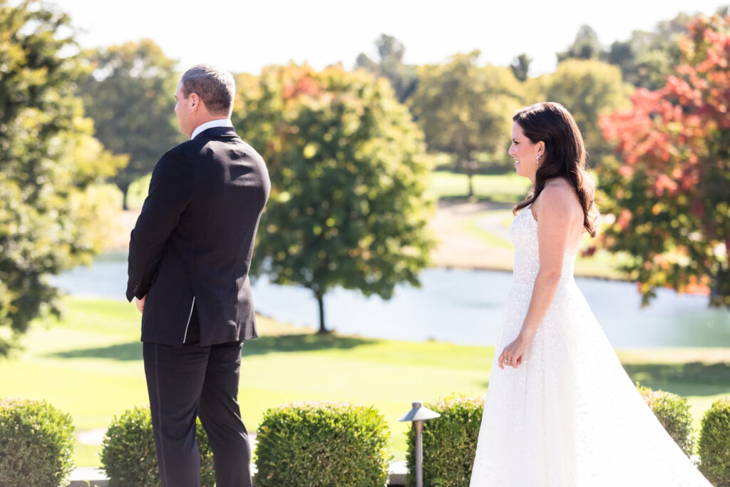 Bride walking up to groom overlooking golf course at Glen Head Country Club. 