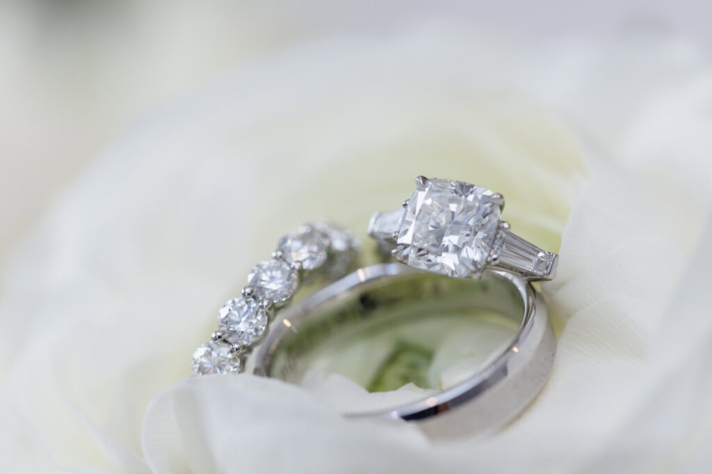 Closeup shot of wedding rings on a white rose. 