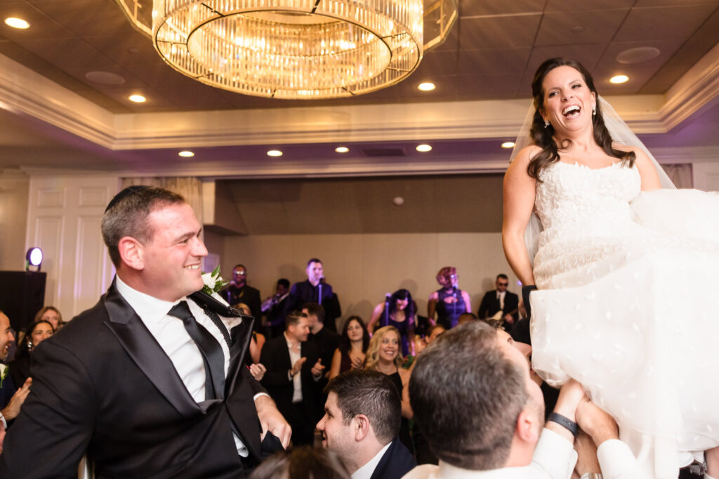 Bride and groom getting lifted during the hora at Glen Head Country Club.