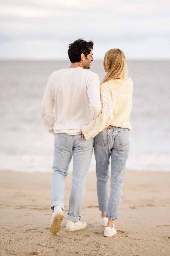 Man and woman walking towards the water on a beach in the Hamptons.