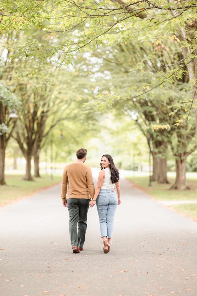 Couple holding hands ad walking away from the camera at Planting Fields Arboretum.