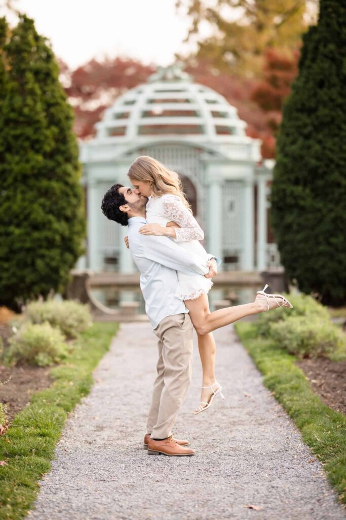 Man lifting woman and kissing at walled garden in Old Westbury Gardens.