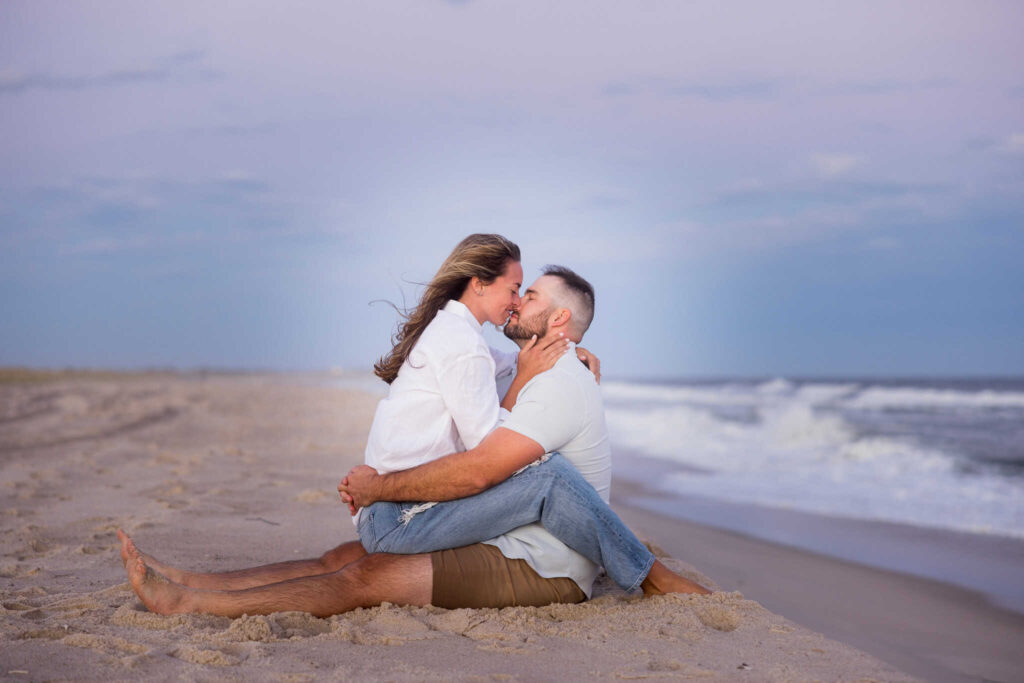 Couple sitting and kissing on the beach. 