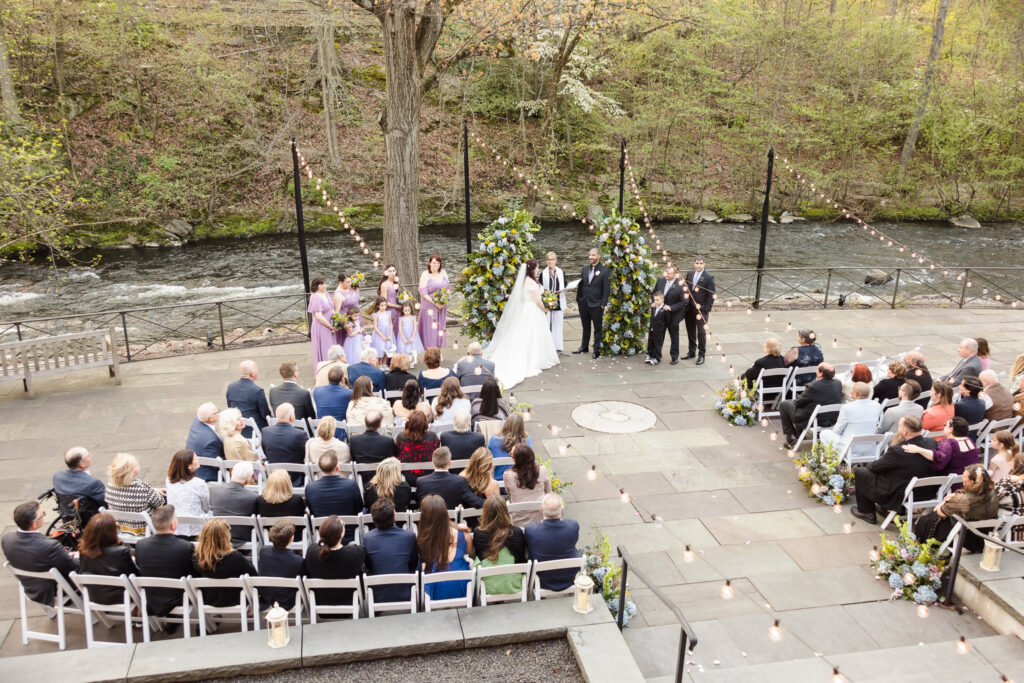 Image of wedding ceremony at Stone Mill at New York Botanical Garden taken from a window above the ceremony. 