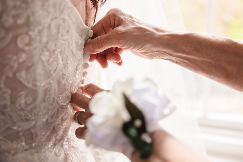 Mother of the bride buttoning dress of bride at Stone Mill Wedding. 