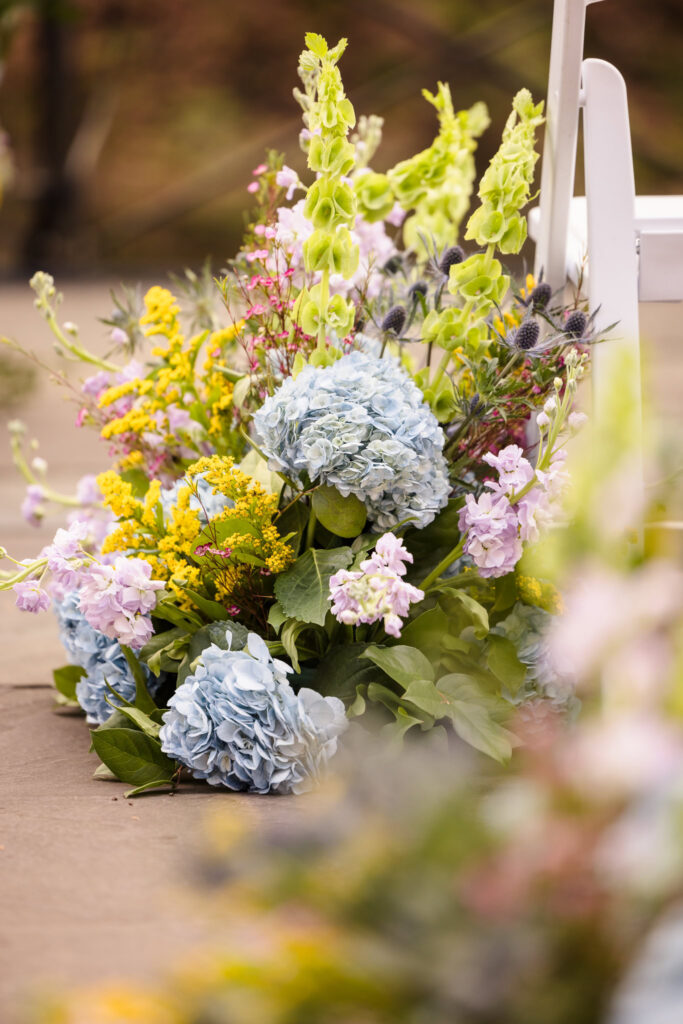 Close up of flowers next to white chairs at Stone Mill at ceremony space at New York Botanical Garden.