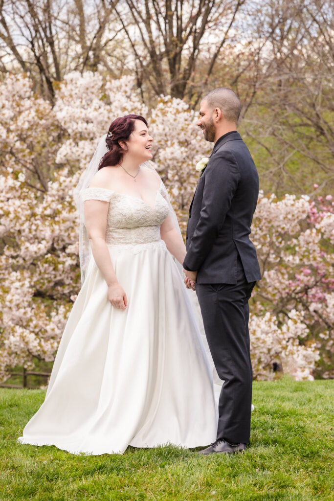 Bride and groom laughing at each other at cherry blossoms at NYBG.