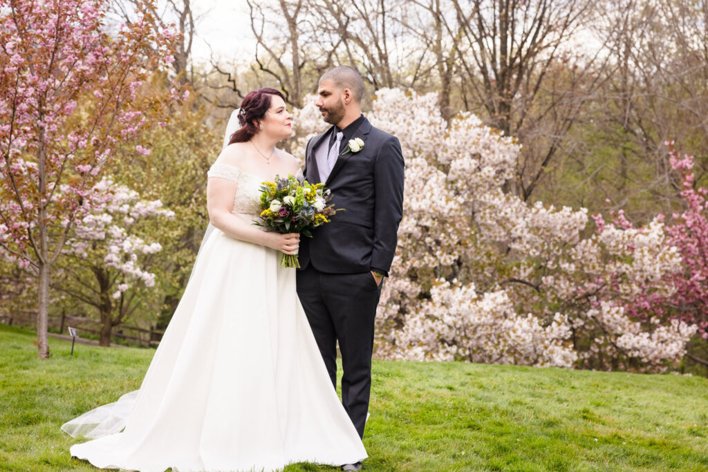 Bride and groom looking at each other surrounded by cherry blossoms at New York Botanical Gardens wedding. 