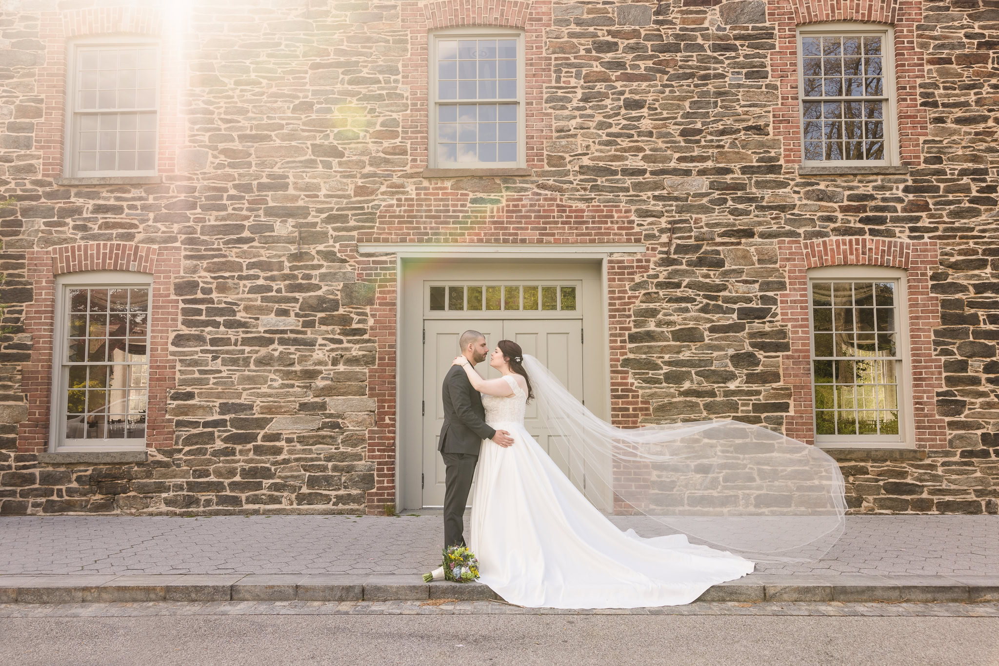 Bride and groom standing in front of Stone Mill at a New York Botanical Garden wedding.