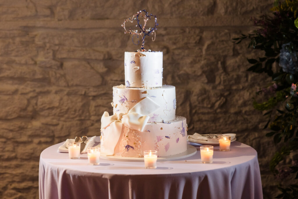 Wedding cake decorated with purple pieces and wire hearts at NYBG Stone Mill wedding. 