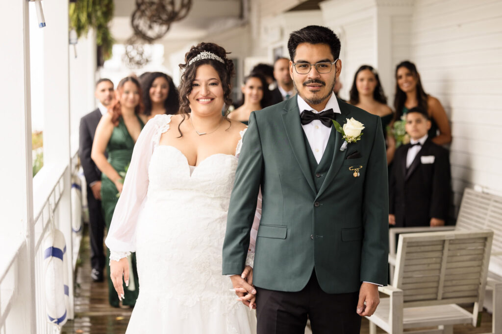 Bride and groom holding hands before the first look at Danford's Hotel while the bridal party is looking on.