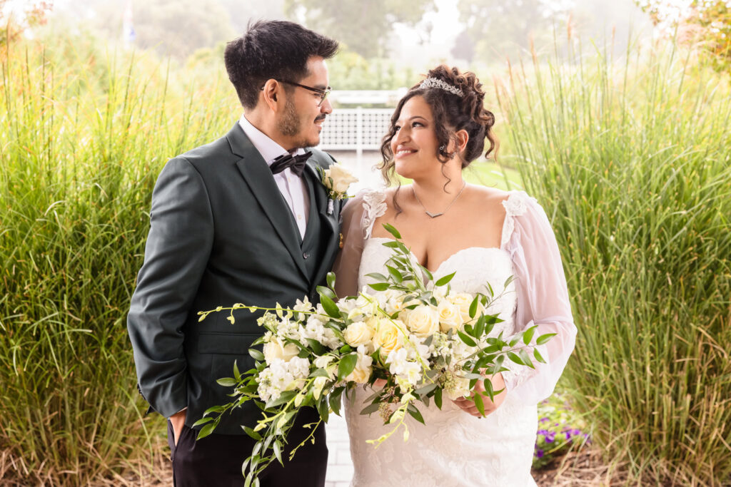 Bride and groom looking at each other and smiling in front of The WaterView at Port Jefferson.