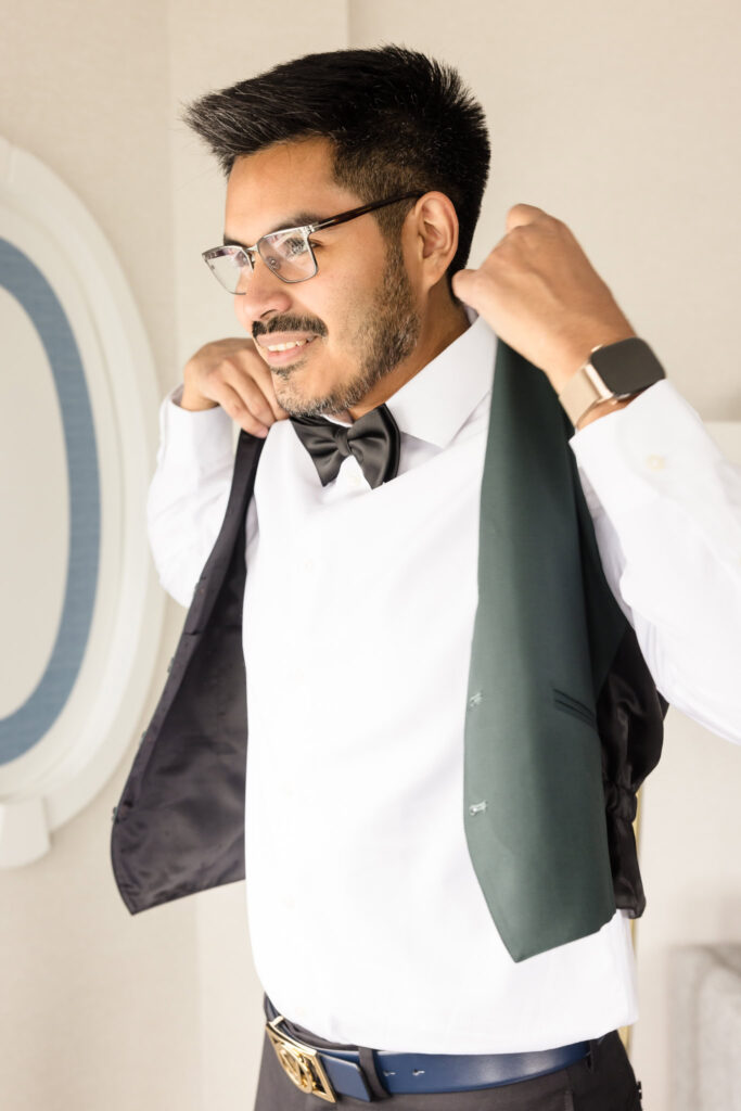 Groom getting ready and putting on his vest.