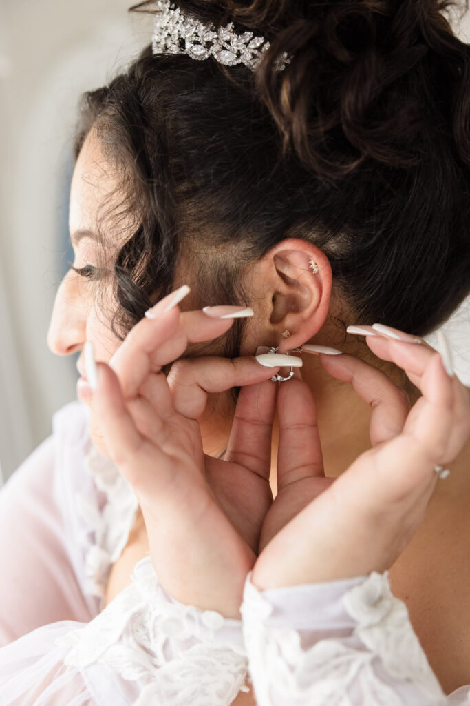 Close up of bride putting on her earrings. 