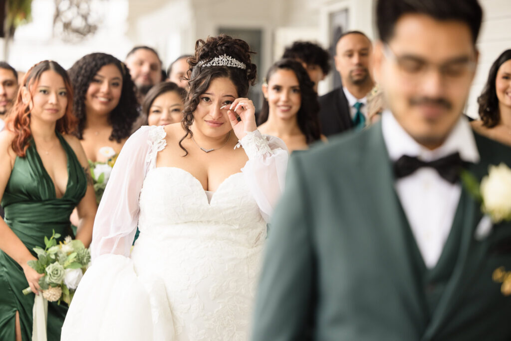 Bride wiping away a tear as she walks toward the groom during the first look at Danford's Hotel.