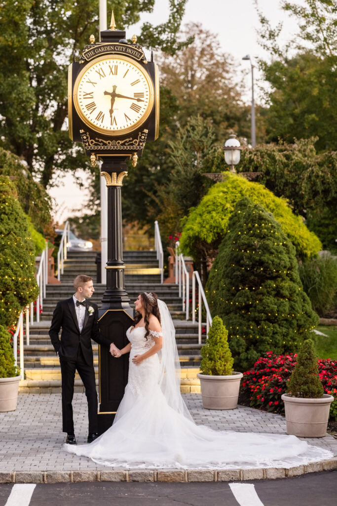 Bride and groom at the clock at the Garden City Hotel. 