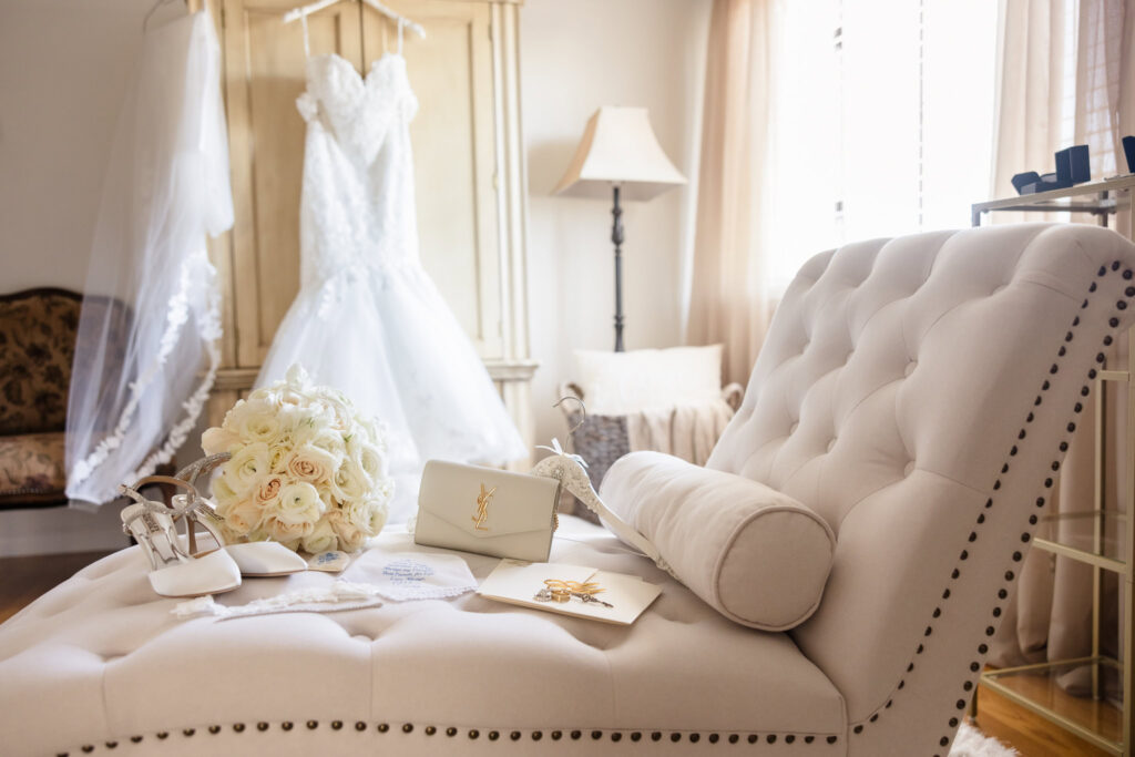 Wedding details, flowers, and dress on a couch at the bride's home.