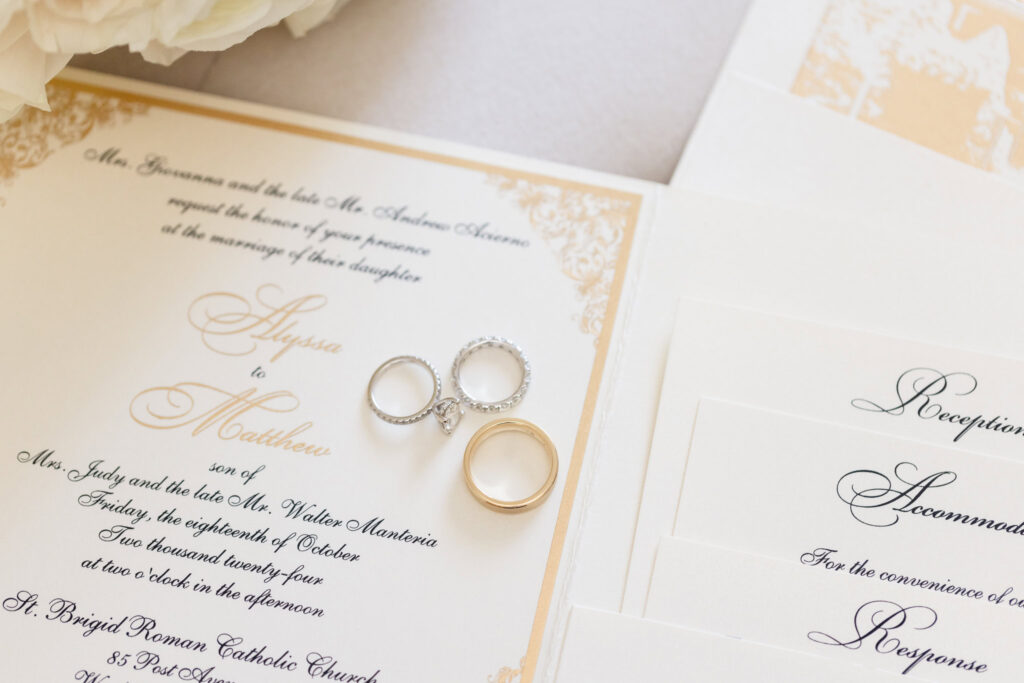 Wedding rings on top of the wedding invitation.