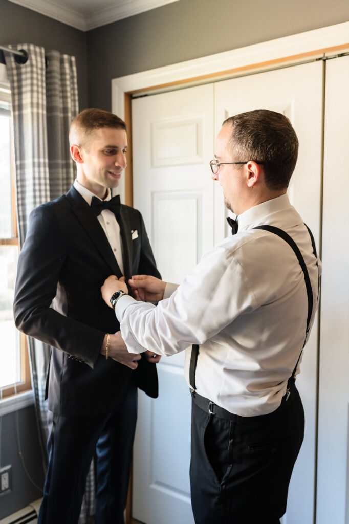 Groom's brother helping the groom get dressed. 