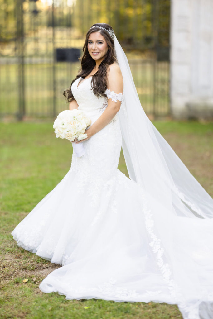 Bride standing in front of gate and looking at the camera at Old Westbury Gardens. 