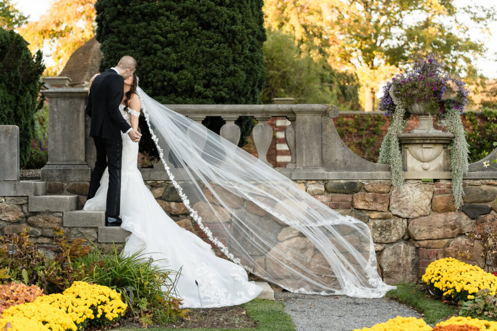 Bride and groom kissing on stone staircase at Old Westbury Gardens. 