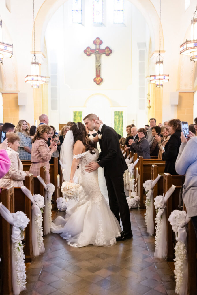 Bride and groom kissing in aisle of St. Brigid's Church after the wedding ceremony. 