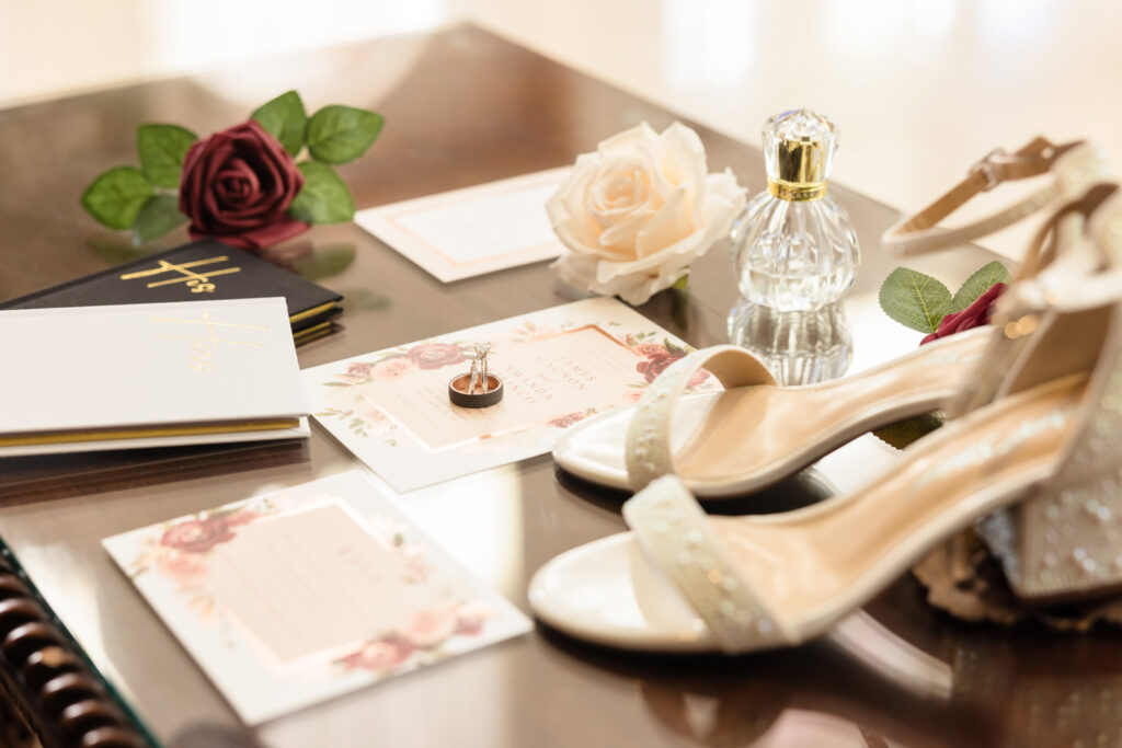 Bride's shoes, invitations, rings, and vow books in the lobby of East Wind Long Island.