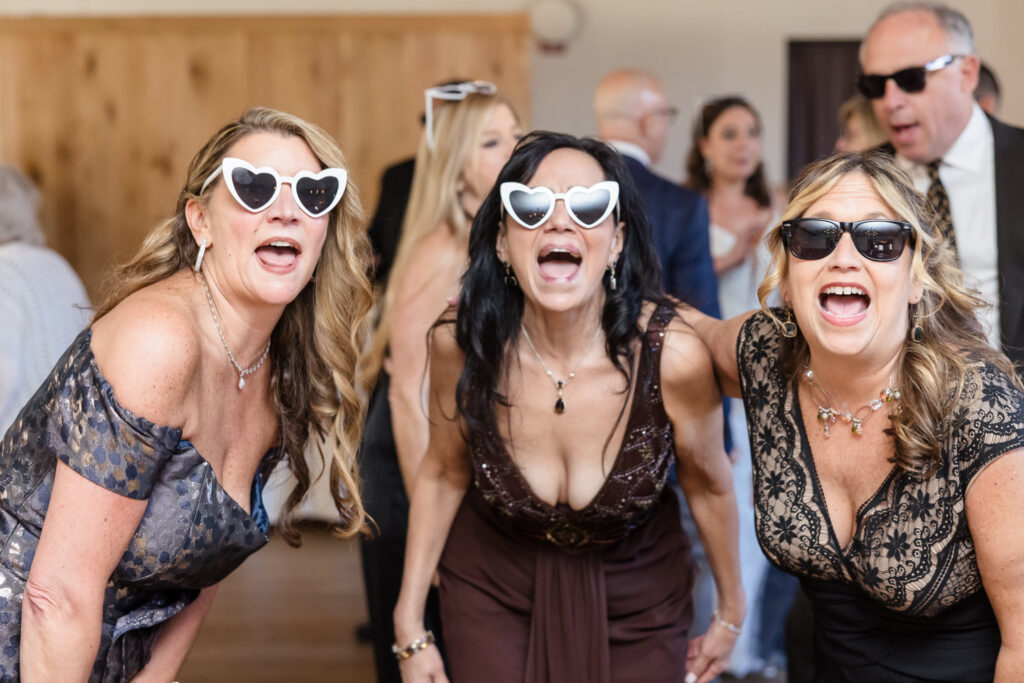 Three women dancing while wearing sunglasses.