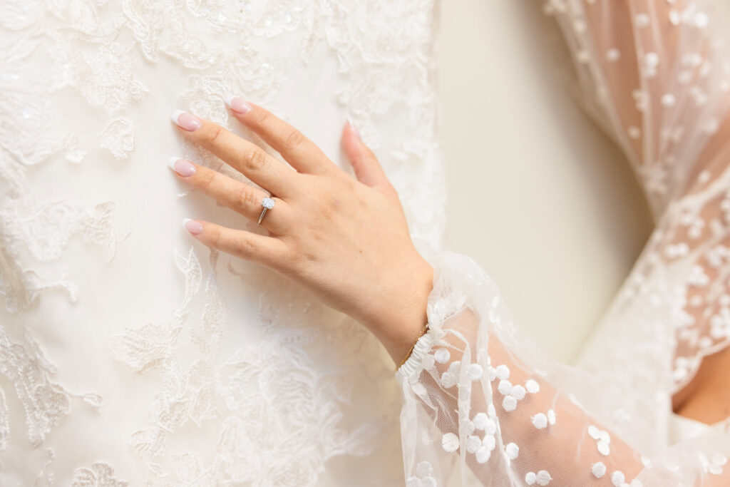 Bride's hand touching her dres.