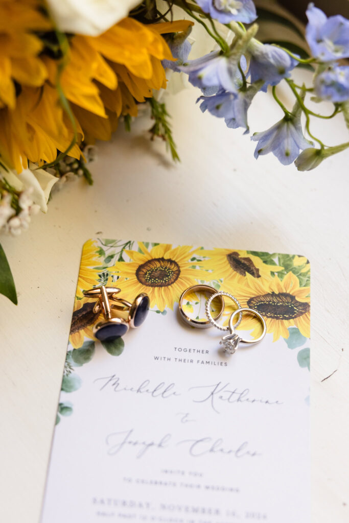 rings placed on invitation next to bridal bouquet