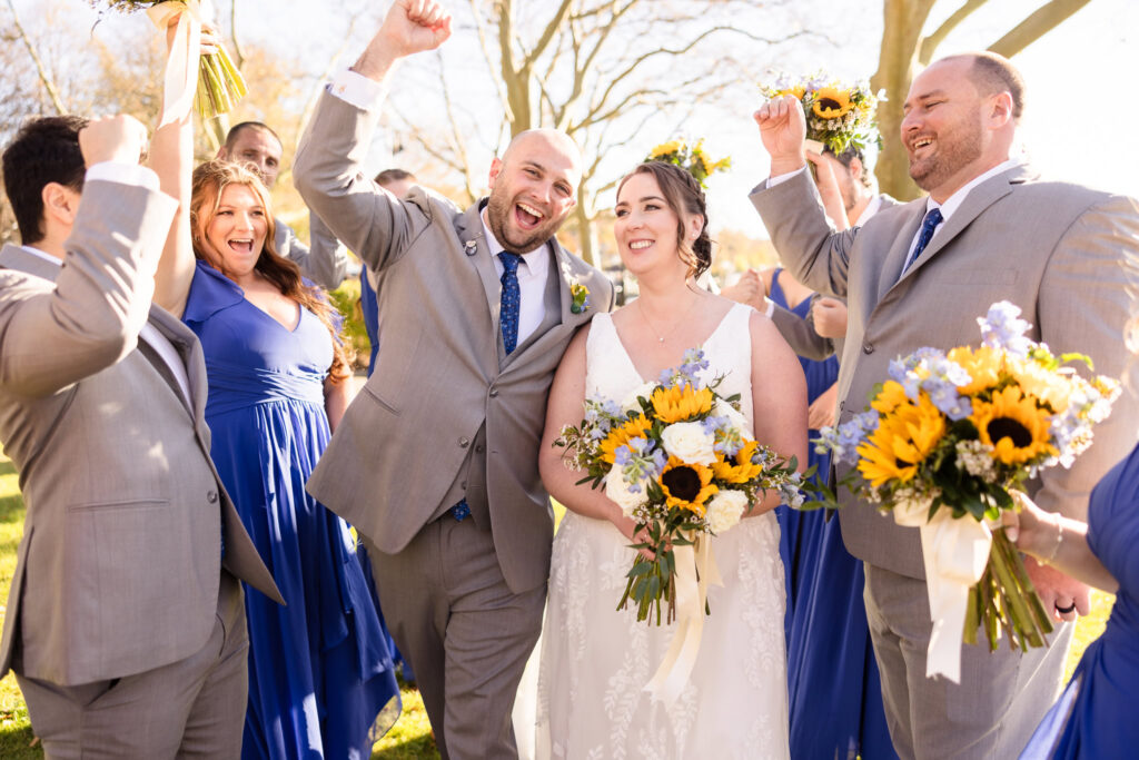 Bride and groom cheering with bridal party and Northport Park. 