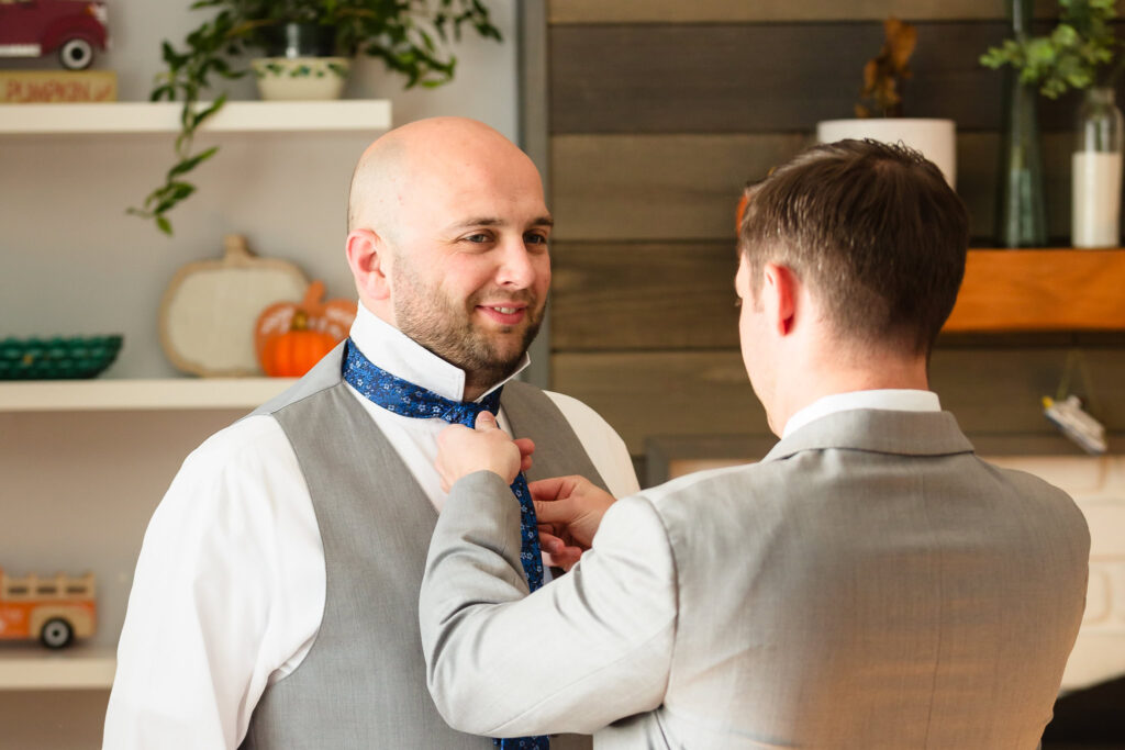 Best man helping groom with his tie.