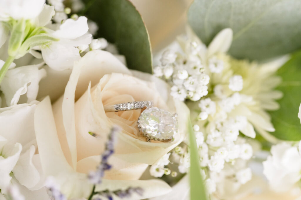 Brides rings on the white flowers of her bouquet.