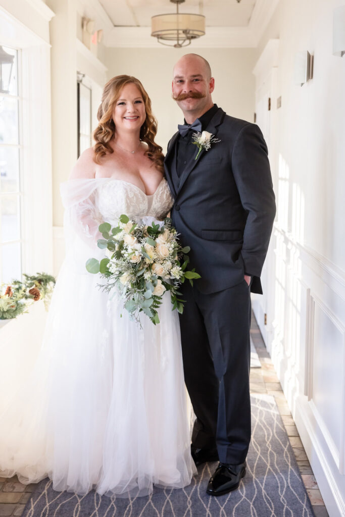 Bride and groom smiling at the camera at the Stewart Manor Country Club.